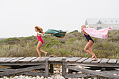 Two girls running on a boardwalk