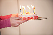 Close-up of a woman's hands holding a birthday cake