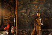 Buddha Statue vor Wandmalerei und Mönch im Hintergrund, Wat Suthat, Altstadt, Bangkok, Thailand