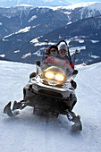 Drei Personen auf einem Schneemobil in den Bergen, Alto Adige, Südtirol, Italien, Europa