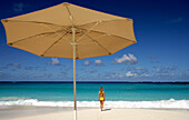 Woman in bikini on beach near umbrella, Anguilla
