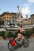 Cyclist checks her guidebook at Neptune Fountain, Piazza Della Signoria, Florence, Tuscany. Italy