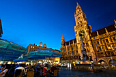 People Eating And Drinking At Cafe Tables In Front Of The Rathaus At Dusk, Marienplatz, Munch, Bavaria, Germany