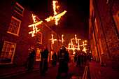 People Dressed As Monks From Southover Bonfire Society Walking In Procession Down Street Carrying Burning Crosses To Commemorate The 17 Protestant Martyrs Burnt At The Stake. Bonfire Night 2009. Lewes, East Sussex, Uk.