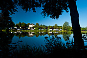 View of camp ground through trees and lake, Normandy, France.