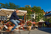 Cyclists passing the riverside cafes, Ljubljana Slovenia