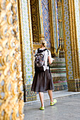 Female tourist at Grand Palace looking at walls of Phra Mondop, Bangkok, Thailand