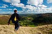 Walker going down hill with view looking along Langdale from near Chapel Stile, Lake District, Cumbria, UK.Walker going down hill with view looking along Langdale from near Chapel Stile