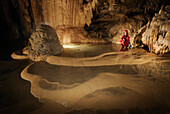Speleology, caving, caver by rimstone pools full of water, Grotte de Gournier (Isere,  France)