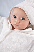 Baby wrapped in white hooded bathrobe