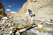 Woman crossing river on a trunk, descent from Yangtang to Rizong, Ladakh, Jammu and Kashmir, India