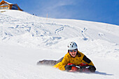 A young woman tobogganing on the toboggan run at the ski resort Stoos, Kanton Schwyz, Switzerland