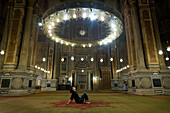 Woman meditating under chandelier in temple, Cairo, Egypt