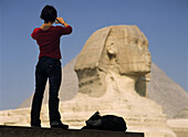 Woman photographing Sphinx and Great Pyramid of Cheops, Giza, Cairo, Egypt
