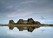 House in between rocks reflected, Brittany, France.