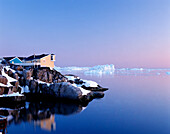 Houses on the coastline with icebergs, Disko Bay, Greenland