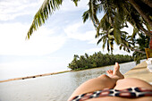 Woman in patterned bikini sunbathing by ocean, Trivandrum, Kerala, India