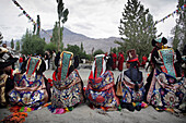 Buddhist Ladakhi women wearing traditional dress and hats with long platted hair and head dress with turquoise stones, Diskyid, Nubra Valley, Leh Ladakh, India