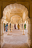 Indian  women in saris walking through columned hallway of the Amber Fort, Jaipur, Rajasthan, India