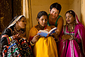 Westerner and women in saris and jewellery looking at guide book, Jaipur, Rajasthan, India