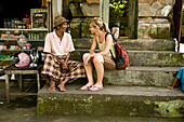 Female tourist sitting with local man, Ubud, Bali, Indonesia