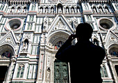 Silhouette of woman taking photograph of the facade of the Duomo, Florence, Tuscany, Italy