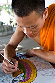 Novice monk drawing pictures of Buddha, Luang Prabang, Laos