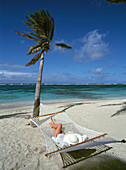 Woman relaxing in hammock on the beach, Nevis