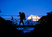 Silhouette of female hiker going across suspension bridge, Mount Aspiring National Park, South Island, New Zealand