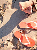 Feet on the beach next to orange flip flops, Libson, Portugal