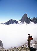 Walker above the clouds looking over Mt. Bulnes de Naranja, Picos de Europa, Spain
