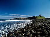 Looking over boulders to Dunstanburgh Castle, Northumberland, England