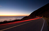Car going down the Big Sur coastal road at dusk, Highway 1, California