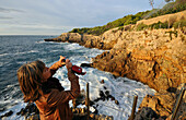 Woman taking a photo of the rocky coast, Le Chemin des Contrebandiers at Cap d´Antibes, Cote d'Azur, South France, Europe