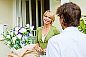 Young women receiving flowers from a young man in front of a house, young couple, Hamburg, Germany