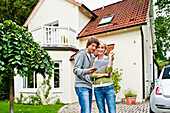 Young couple is looking at documents in front of a house, Hamburg, Germany