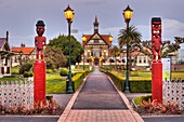 Rotorua Museum entrance pathway lined by lamps and Maori wooden carved figures, dusk, Government gardens, Rotorua