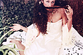 Junge brünette Frau in weißem Kleid auf einer Decke auf dem Boden sitzend, Porträt