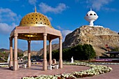 A gold dome cupola shelter and the incense burner landmark overlooking the Corniche promenade in Muscat, Oman