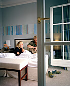 Paar auf einem Doppelbett in einem Hotelzimmer, Arosa Spa Resort Travemünde, Travemünde, Lübeck, Schleswig-Holstein, Deutschland