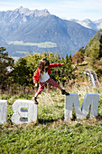 Girl balancing on concrete letters near Ecohotel, Am Hochpillberg, Schwaz, Tyrol, Austria