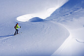 Woman backcountry skiing crossing a snowface, Nadernachjoch Skitour, Neue Bamberger hut, Kitzbuehel Alps, Tyrol, Austria