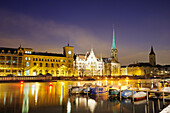 Illuminated buildings, churches Frauenmuenster and St. Peter with river Limmat in foreground, Zurich, Switzerland