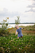 Little boy walking an the lawn near lake Cospudener, discovering the world, Leipzig, Saxony, Germany