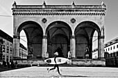 Surfer girl in Munich in front of the Feldherrnhalle, Odeonsplatz, Munich, Bavaria, Germany