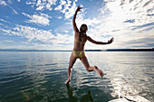 Girl jumping into Lake Starnberg, Bavaria, Germany