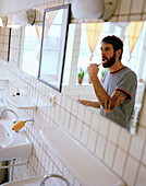 Man brushing his teeth in the shared bathroom of a one star Hotelroom, Zeeburg, Amsterdam, Netherlands