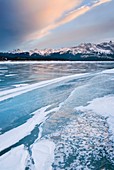 Clouds glowing in a winter sunset over the wind polished ice of Abraham Lake, Alberta Canada