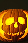 Close up of an illuminated Halloween pumpkin showing a skull