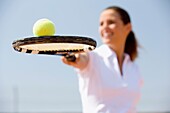 ability, adult, balance, ball, brunette, Close-up, Color image, contemporary, dark hair, day, equilibrium, Female, fit, holding, horizontal, human, In good shape, In shape, Keeping fit, know-how, leisure, one, one person, outdoor, people, player, racket, 